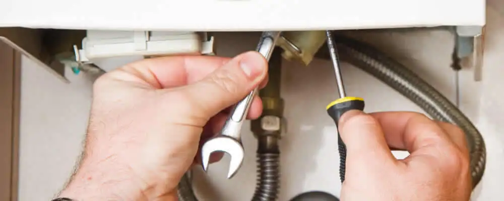 Boiler repair technician tightening pipe fittings and connections in Long Beach, CA