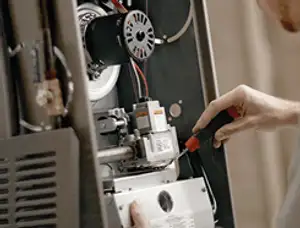 Furnace repair technician inspecting internal components and wiring in Long Beach, CA