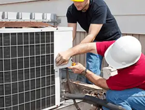 HVAC technicians repairing an outdoor AC unit on a rooftop in Long Beach, CA