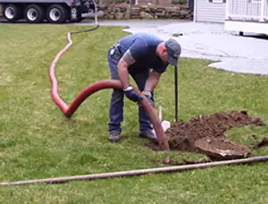 Septic pumping technician servicing a residential septic tank with a vacuum hose in Long Beach, CA