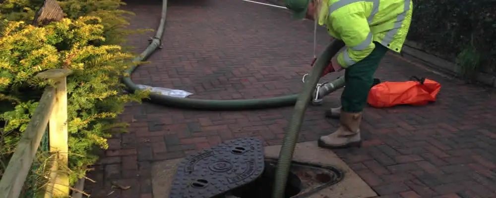 Septic tank cleaning technician servicing a septic tank with a vacuum hose in Long Beach, CA