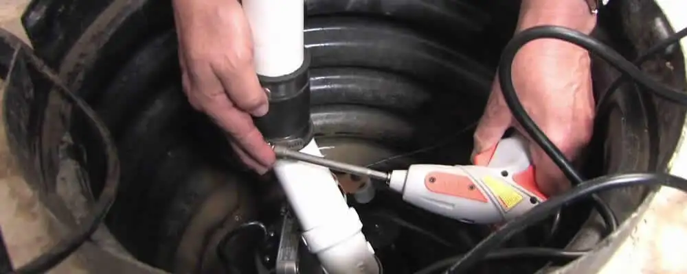 Sump pump installation technician connecting PVC discharge piping in Long Beach, CA