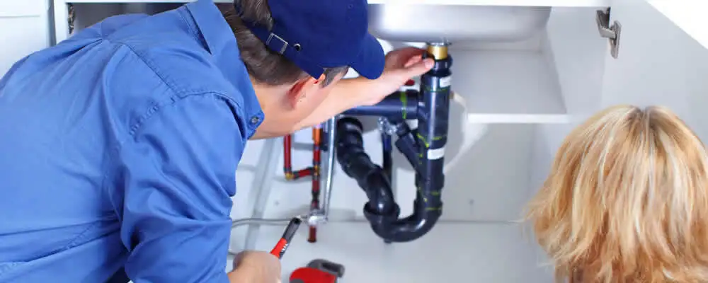 Plumber repairing under-sink drain pipes and fittings in Long Beach, CA